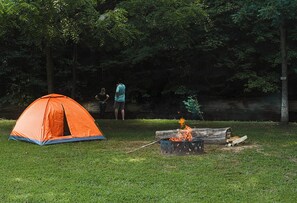 An orange tent set up on grass with a campfire nearby. - Camping in the Hocking Hills at Altenbrauch Farm (McArthur)