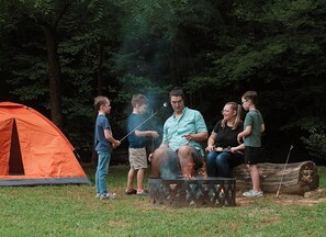 A group of people around a campfire in a forested area with a tent. - Camping in the Hocking Hills at Altenbrauch Farm (McArthur)
