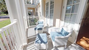 Ein überdachter Balkon mit weißen Korbmöbeln und einem weißen Geländer.