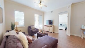 Ein Wohnzimmer mit einer Couch, einem Sessel, einem Fernseher und einem Holzschrank.