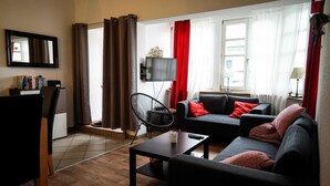 Ein Wohnzimmer mit einer Couch, einem Couchtisch, einem Fernseher und einem Sessel.