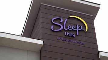 A Sleep Inn sign with a stylized sun logo, indicating a hotel by Choice Hotels.