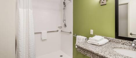 A bathroom with a shower, a sink, and a mirror.