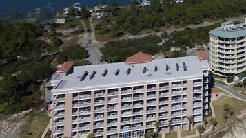 A large hotel with multiple floors, a swimming pool, and a view of the ocean.