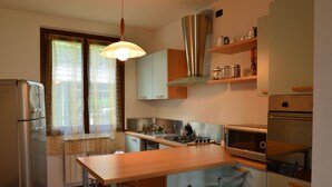 Une cuisine compacte équipée d’un réfrigérateur, d’une cuisinière, d’un four à micro-ondes et d’une table à manger avec des chaises.