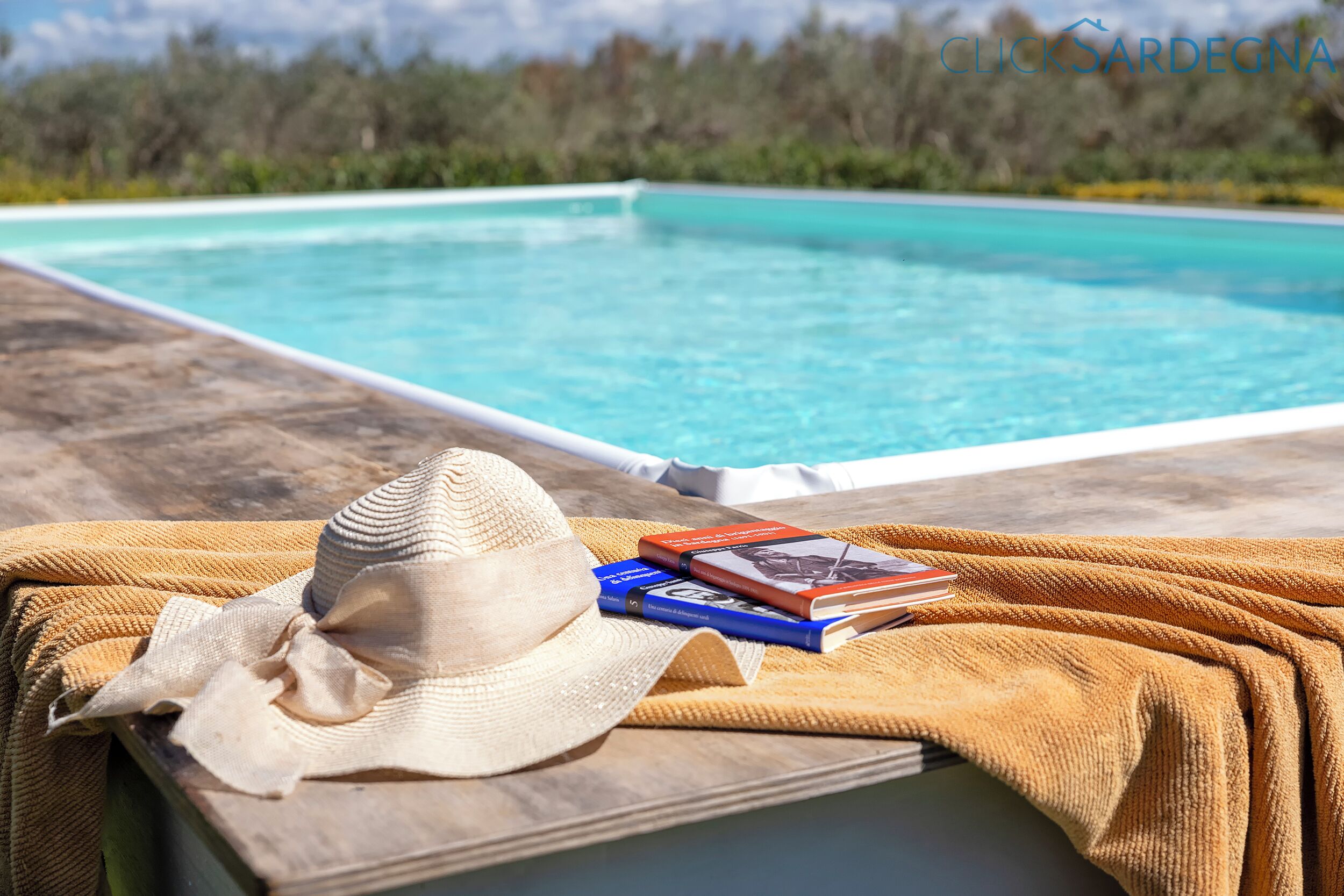 A poolside setting with a hat, books, and a towel.
