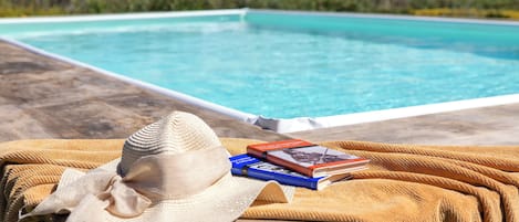 A poolside setting with a hat, books, and a towel.