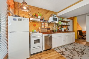 Une cuisine de taille réduite, avec des appareils électroménagers blancs, des meubles en bois et un tapis à motifs.