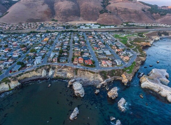Vue aérienne d’une zone résidentielle côtière, avec des maisons, des routes et une plage.