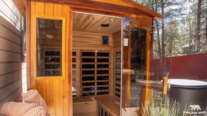 Een sauna met houten wanden en een glazen deur, een bankje en een prullenbak met de tekst 'Polar Dive USA'.