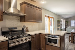 A modern kitchen with stainless steel appliances, wooden cabinets, and a tiled backsplash.