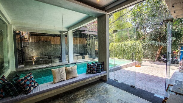 A modern interior with a glass wall overlooking a pool and garden. - Stellar Capsules - Hostel (Seminyak)