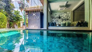 A pool area with a sign reading "STELLAR CAPSULES" and another sign with "SVBANGEL SVB". - Stellar Capsules - Hostel (Seminyak)