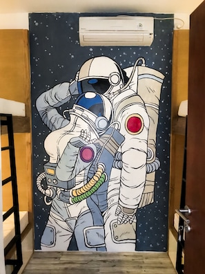 A space-themed shower curtain with an astronaut design, featuring a space suit and a smaller figure. - Stellar Capsules - Hostel (Seminyak)