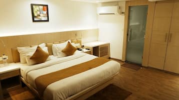 A hotel room with a large bed, bedside tables, a wardrobe, and a wall-mounted air conditioning unit.