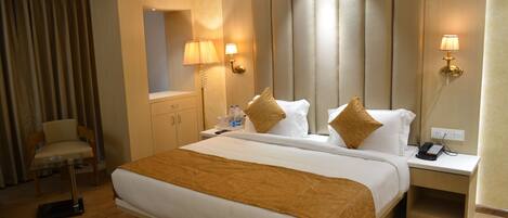 A hotel room with a large bed, a bedside table with a lamp, a chair, and a mirror.