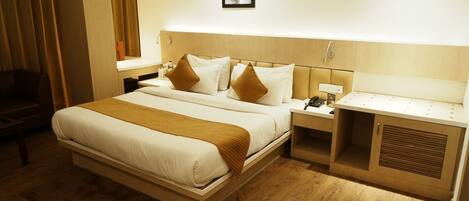 A hotel room with a large bed, bedside tables, a desk, and a chair.