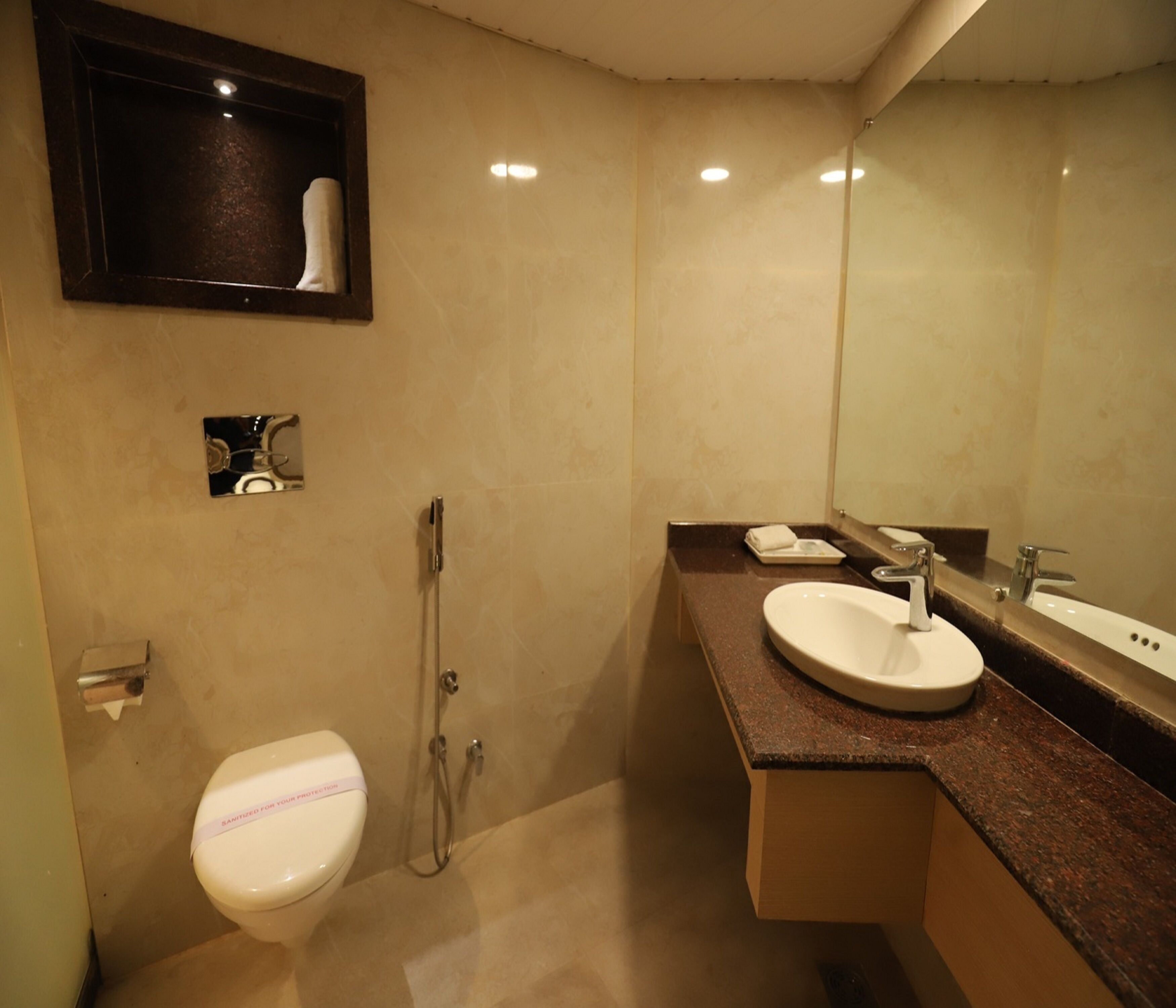 A bathroom with a toilet, a sink, a shower, and a mirror.