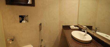 A bathroom with a toilet, a sink, a shower, and a mirror.