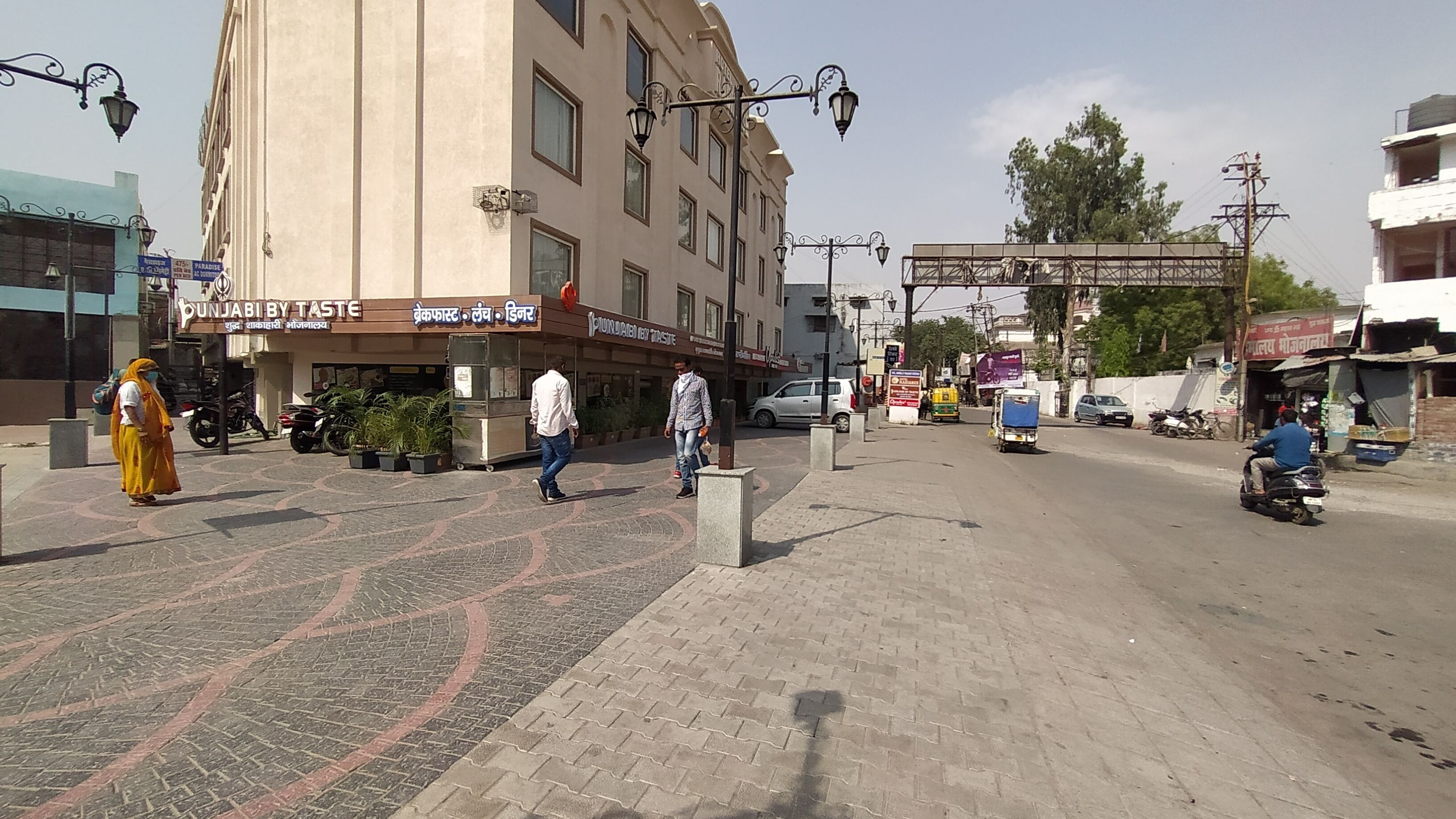 Una calle con un edificio que dice 'Punjab by Taste', con un cartel que muestra texto en varios idiomas.