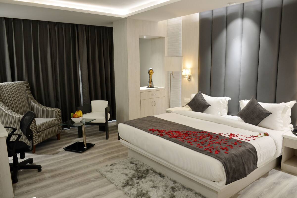 A hotel room with a bed, a chair, a desk, and a mirror.
