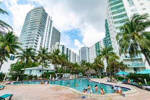 A swimming pool surrounded by palm trees and high-rise buildings.