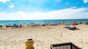 A beach with people, umbrellas, and a wooden structure. - Beachfront Apt | Balcony + Pool | 4 adults + kids (Hollywood)