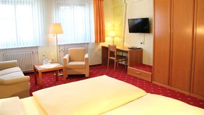 Une chambre d’hôtel comprenant un lit, un bureau, une chaise, une télévision et une armoire.