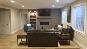 Ein Wohnzimmer mit einem braunen Ledersofa, einem blauen Sessel und einem an der Wand befestigten Fernseher.