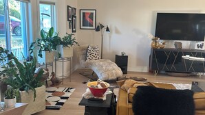 A living room with a sofa, a TV, and a fireplace. There are potted plants and a rug on the floor. - Luxury open concept Vacation Home. Close to downtown ,Old Mill trails & parks. (Bend)