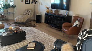 A modern living room with a large flat-screen TV, a comfortable sofa, a coffee table, and a decorative rug. - Luxury open concept Vacation Home. Close to downtown ,Old Mill trails & parks. (Bend)