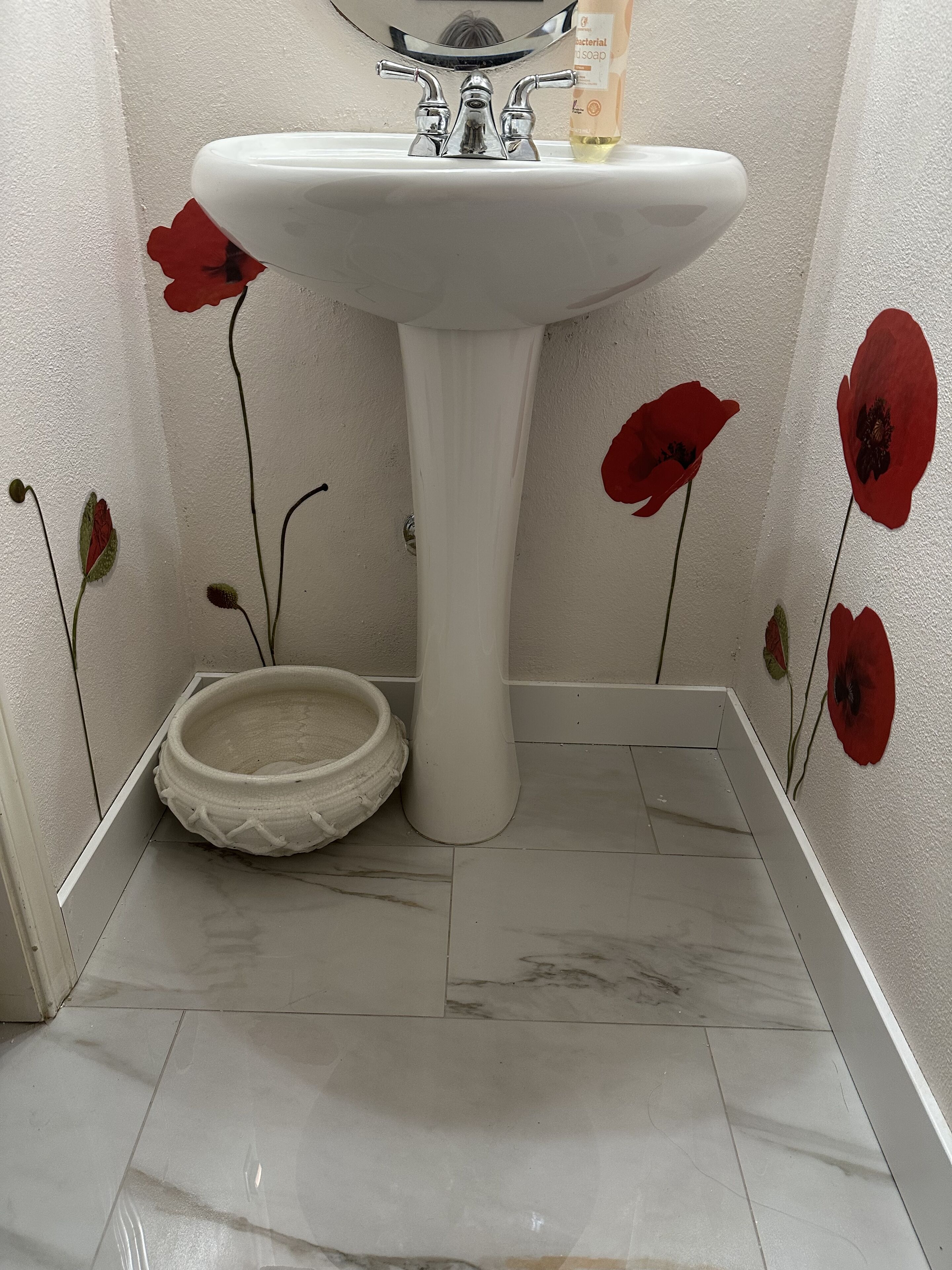 A bathroom with a white pedestal sink, a soap dispenser, and a white basin.