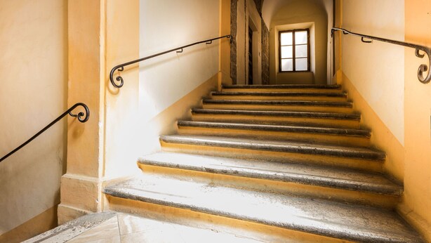 Eine Treppe mit Handlauf und einem Fenster am Oberende.