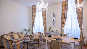 Ein Wohnzimmer mit einer Couch, einem Esstisch und Stühlen. Über dem Tisch hängt eine Pendelleuchte.