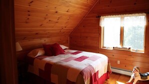 Un dormitorio de cabaña de madera acogedor, con cama, ventana y un caballito de juguete.