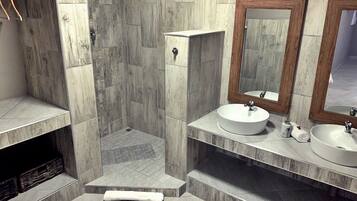 A bathroom with two sinks, a shower, and a wooden cabinet.