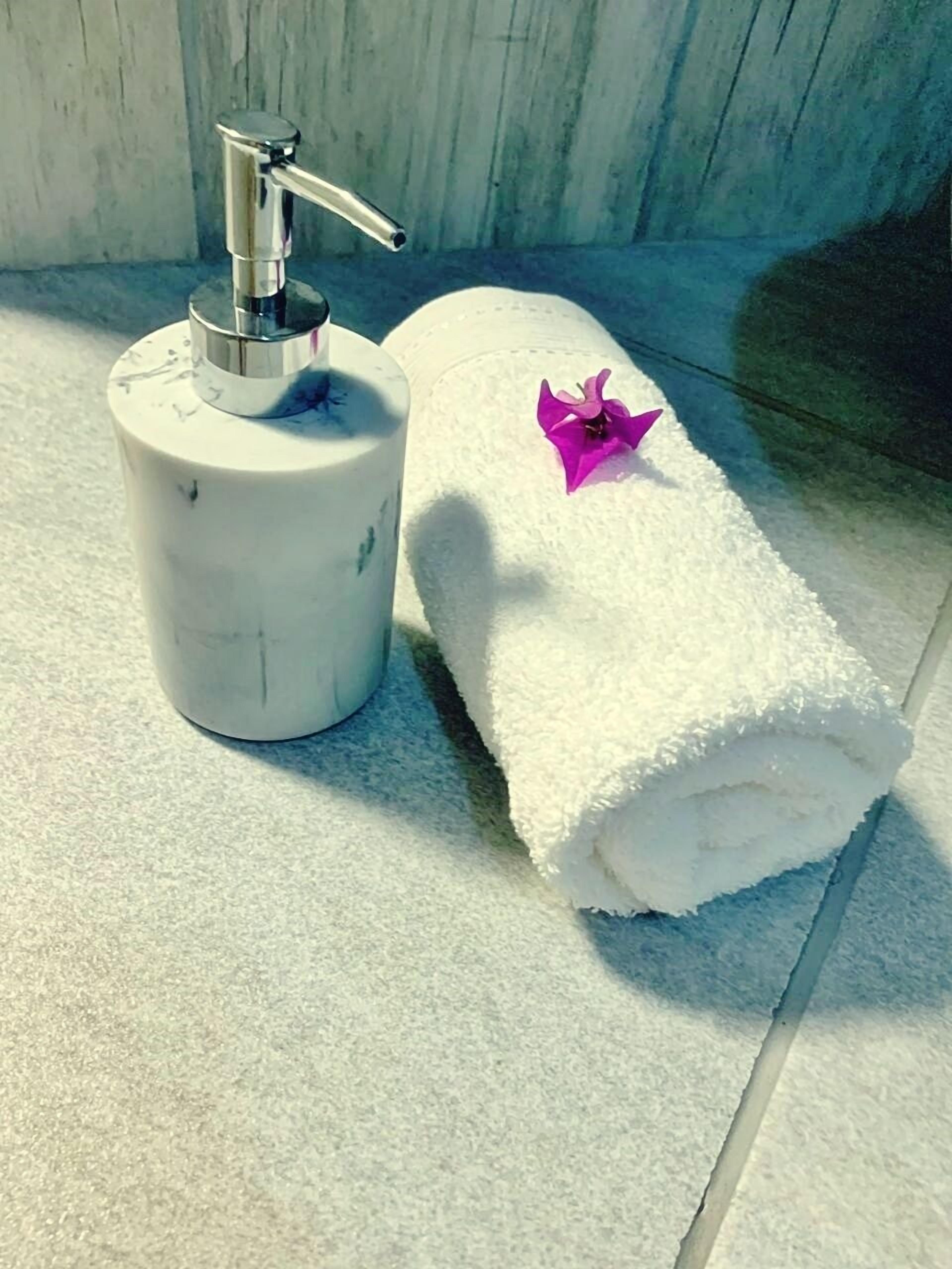 Un baño con una toalla blanca y un dispensador de jabón con bomba.