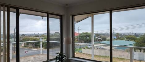 A room with large windows offering a view of a road and surrounding buildings.