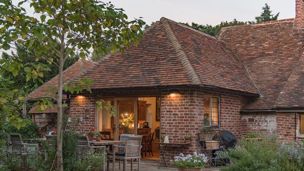 Une maison en briques avec un patio, un espace salon extérieur et un jardin.