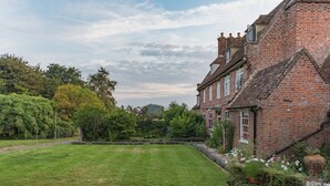 Une maison traditionnelle en briques, dotée d’une pelouse et d’un jardin bien entretenus.