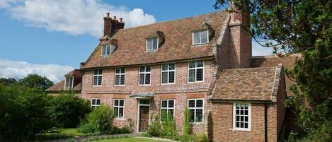 A large brick house with multiple windows and a well-maintained lawn.