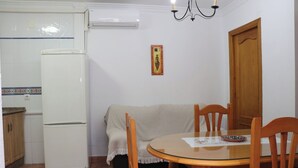 Una cocina compacta con refrigerador, una mesa de comedor con sillas y una araña.