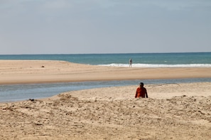 A beach with a person in a red garment standing on the sand, a calm sea, and a clear sky. - Apartment with air-con in lounge (CONIL DE LA FRONTERA)