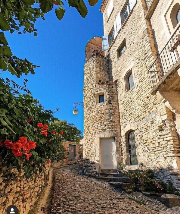 A stone building with a tower, a cobblestone path, and red flowers.