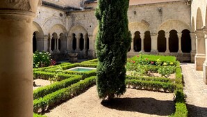 Un patio con arquitectura de piedra, una fuente central y setos bien cuidados.