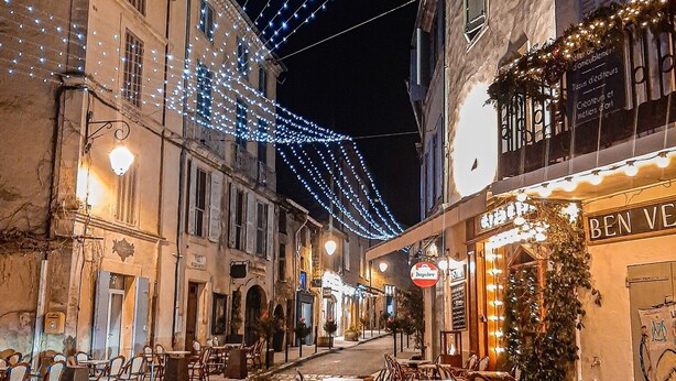 Una calle adoquinada con mesas al aire libre y luces colgantes.