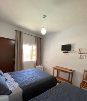 A bedroom with two beds, a TV, a desk, and a window with curtains. - Estrela D'Alva Pousada (Pirenópolis)