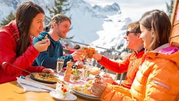 Un groupe de personnes déjeunant en plein air, avec une montagne en toile de fond.