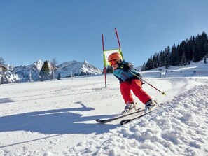 Una persona esquiando en una pendiente nevada con montañas al fondo.