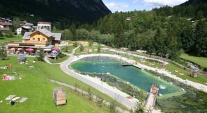 Un resort con una piscina grande, un restaurante y vistas al bosque y las montañas circundantes.